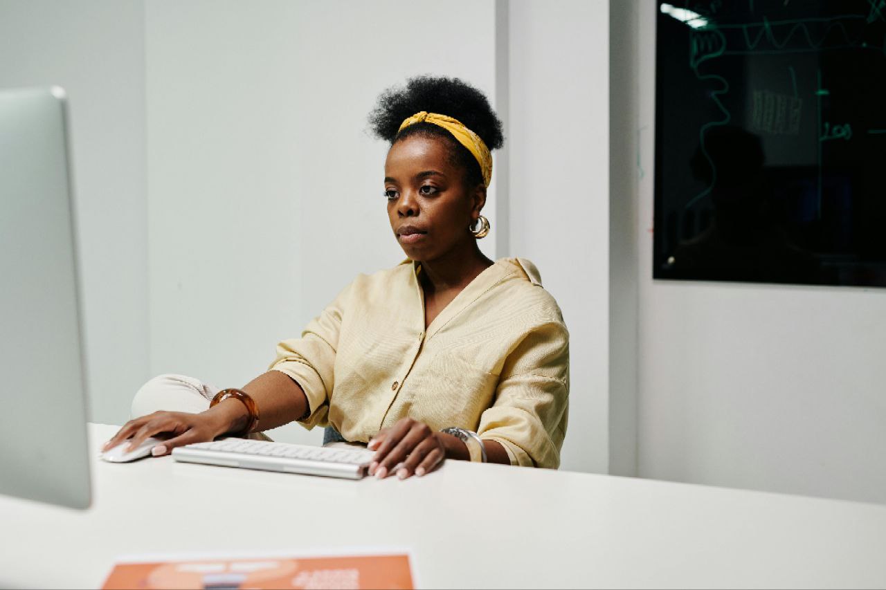 Professional woman in yellow outfit working at desk with keyboard